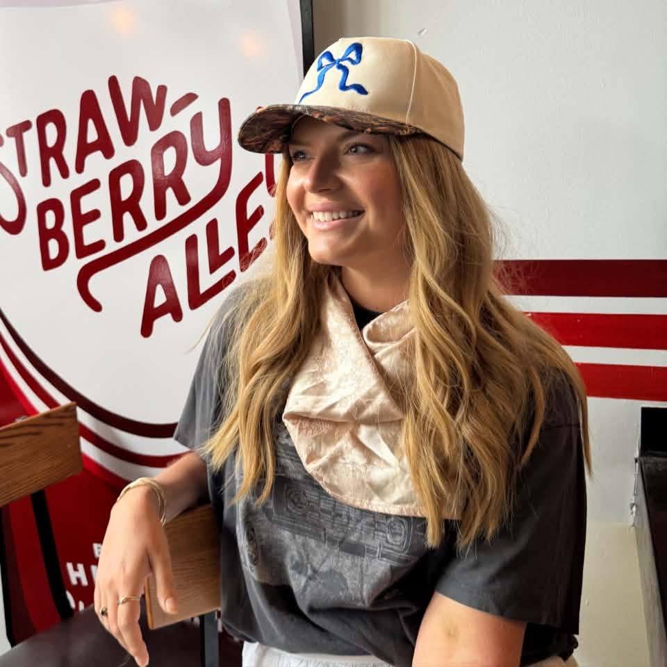 Kristin smiling in a ball cap at Strawberry Alley